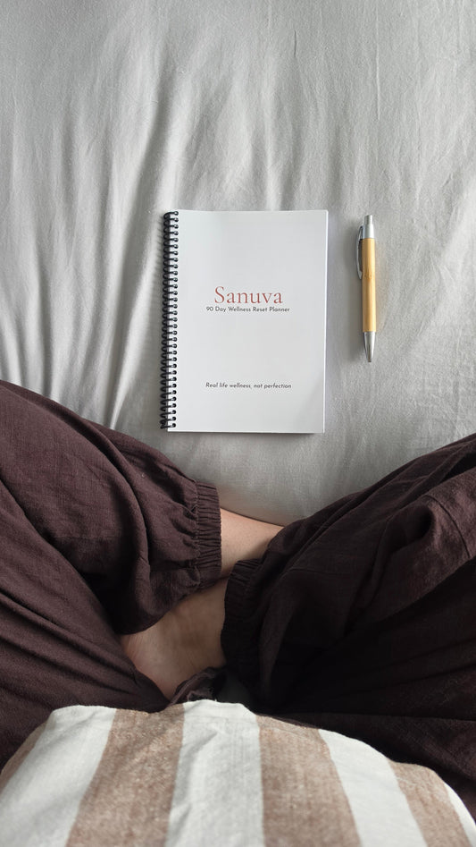 Someone sitting cross legged in front of a planner and pen