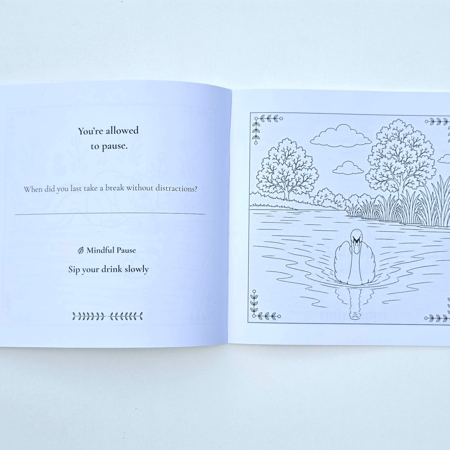 An open journal with text on the left side and a colouring page on the right of a swan in a lake.