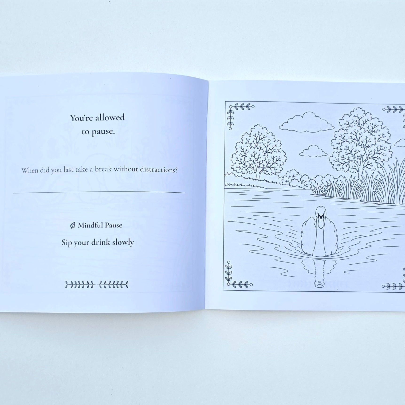 An open journal with text on the left side and a colouring page on the right of a swan in a lake.