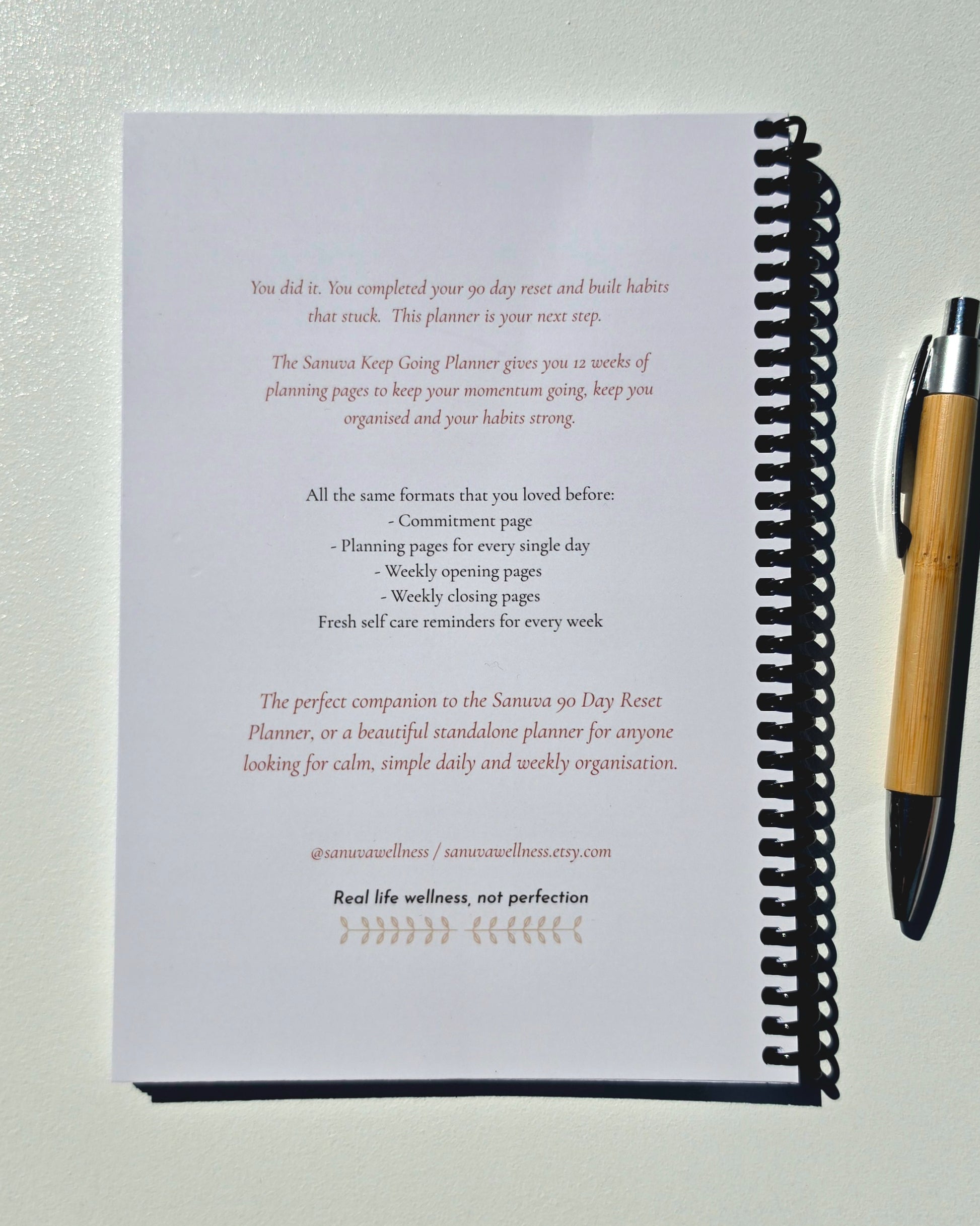 A spiral bound book with a bamboo pen showing a blurb