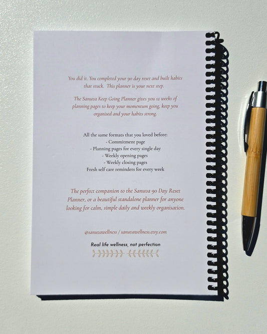 A spiral bound book with a bamboo pen showing a blurb